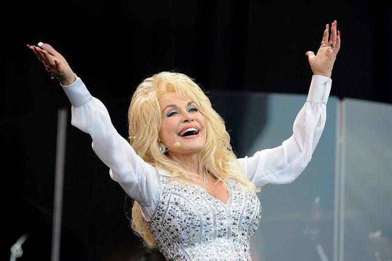 Dolly Parton en el escenario con los brazos levantados